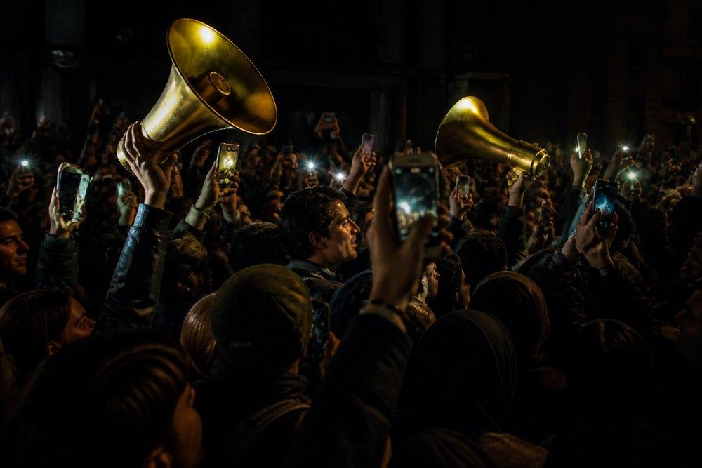 A night crowd competing with phones and megaphones.