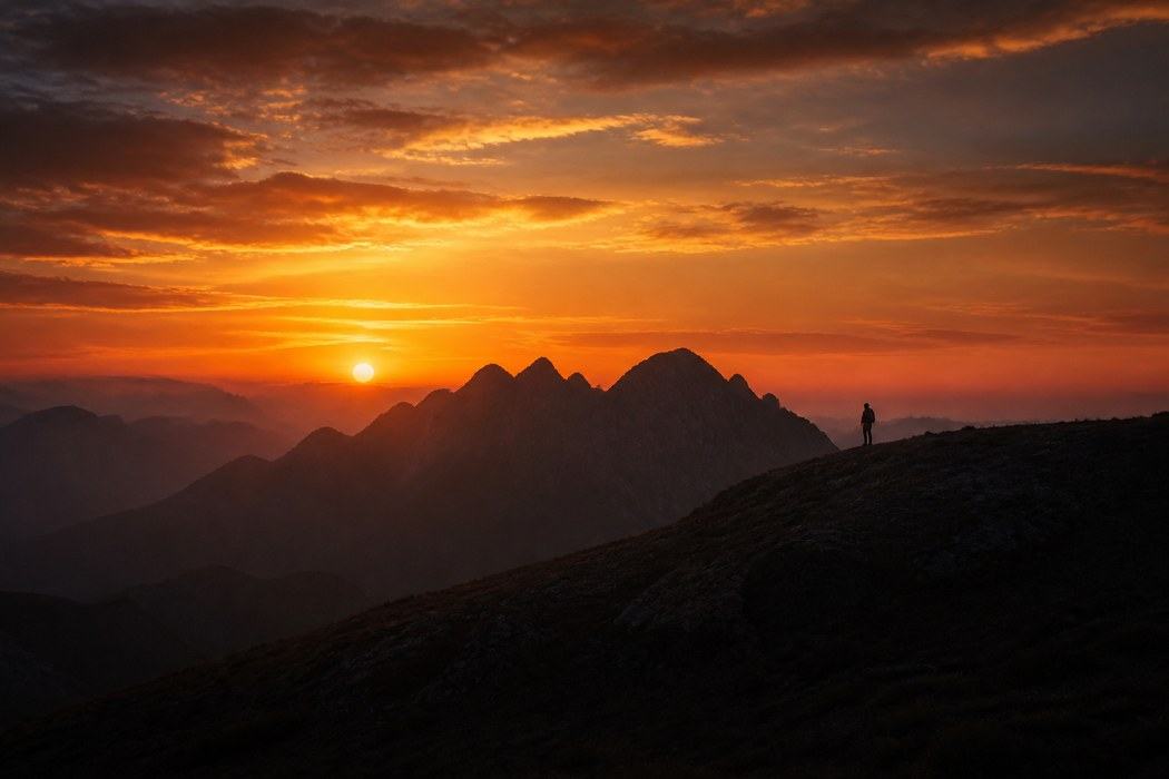 A figure on a ridge facing first light.